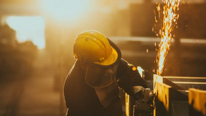 Metal işleme sırasında koruyucu ekipmanla çalışan görevli