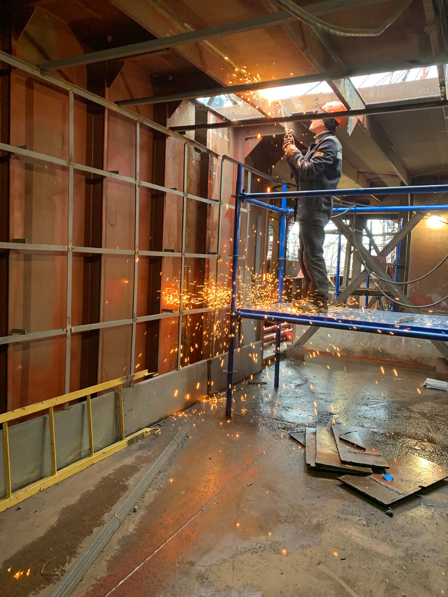 Metal yapı üzerinde koruyucu ekipmanla kesim işlemi yapan çalışan